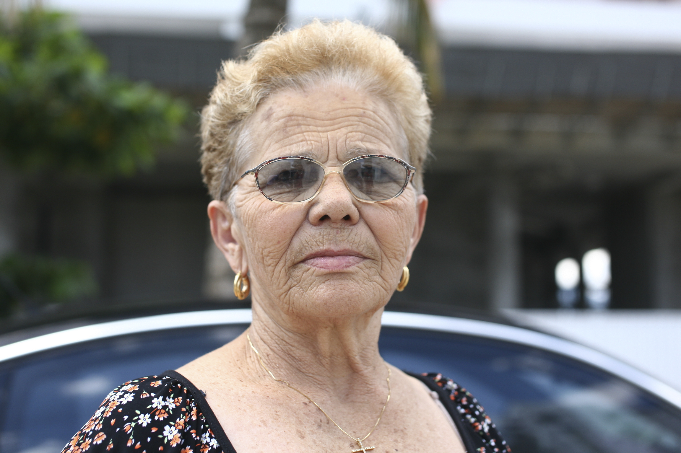 an old woman in front of a parked car