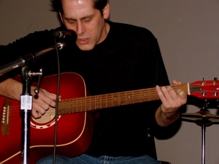 a man playing a guitar while sitting in front of a microphone