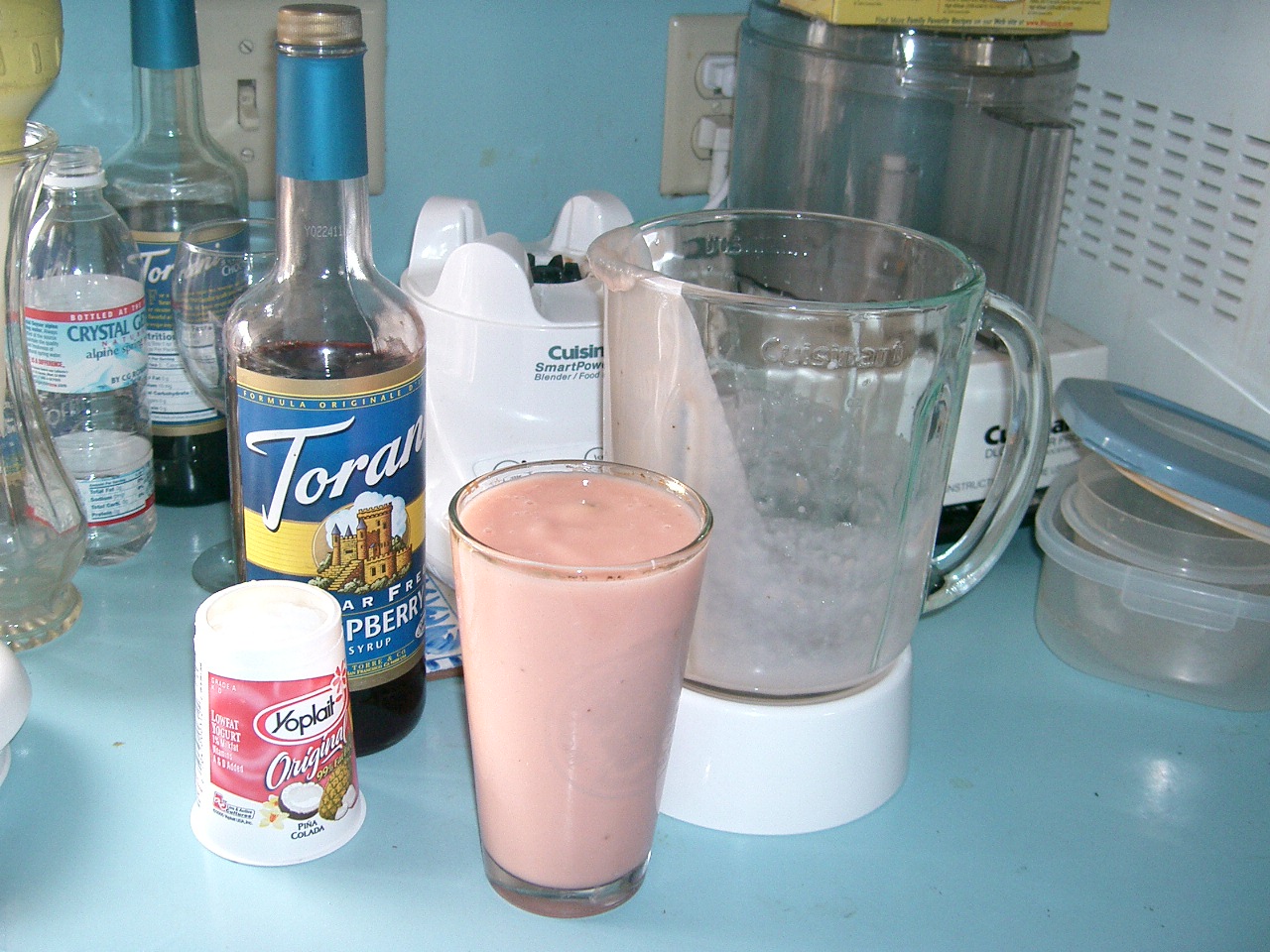 a pitcher of liquid, some bottles, and other items on a table