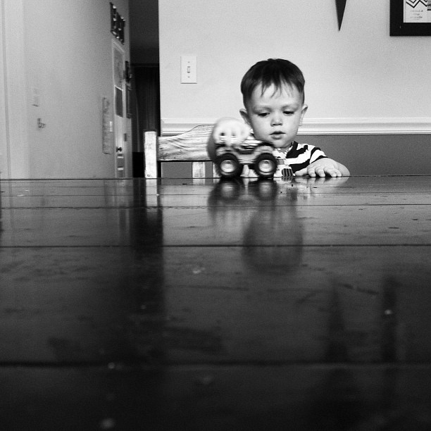 a little boy laying on the floor in front of his toy truck