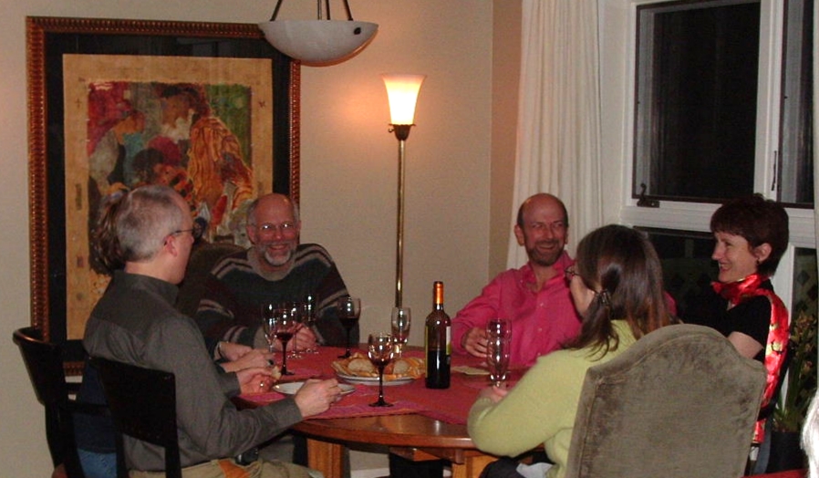 group of people sitting around a small table drinking wine