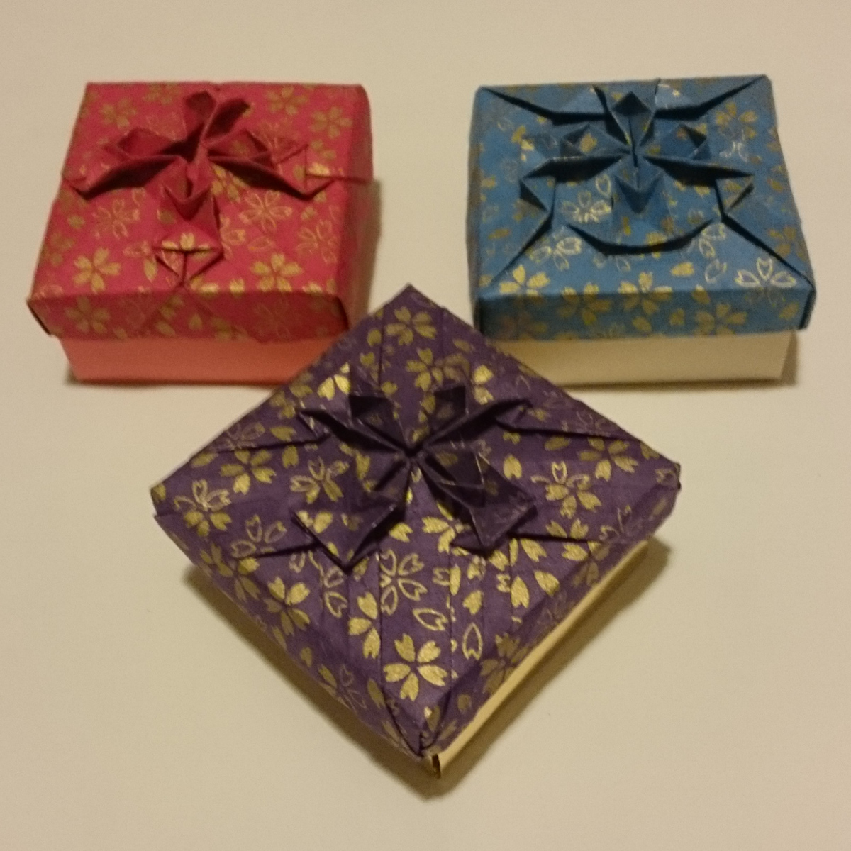 three different colored boxes sitting on top of a white table