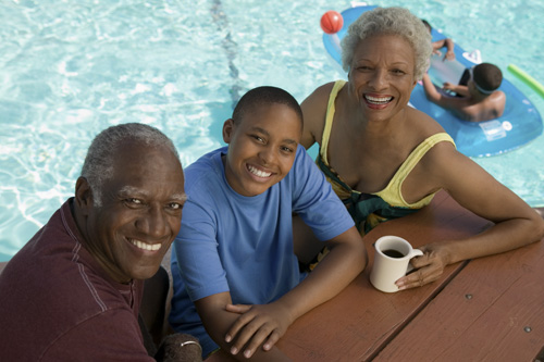 an old man and two young children by the edge of a swimming pool