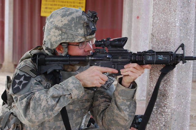 a soldier holding a rifle, aiming it through its muzzle