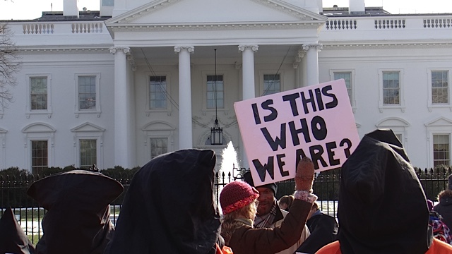 people wearing black robes stand in front of the white house