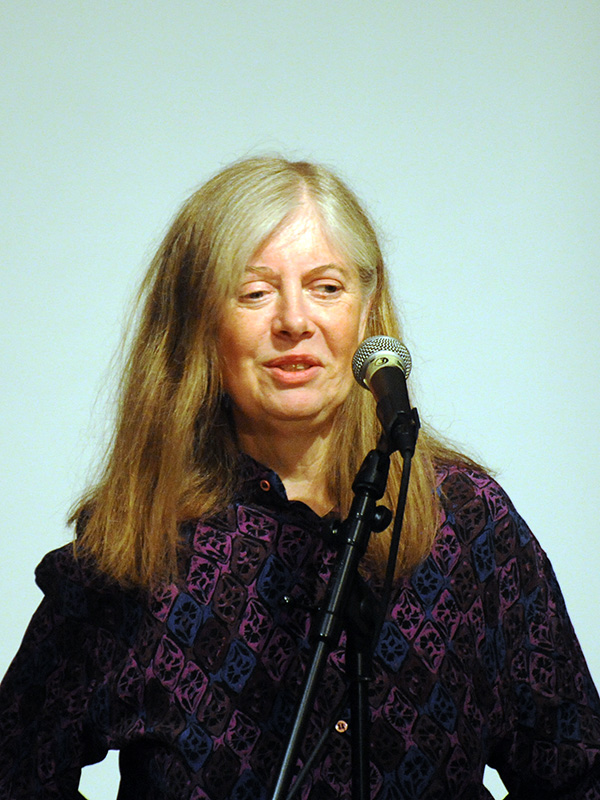 a woman in purple holding a microphone and speaking