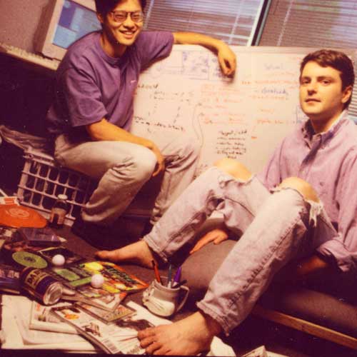 two young men sitting at a desk with papers