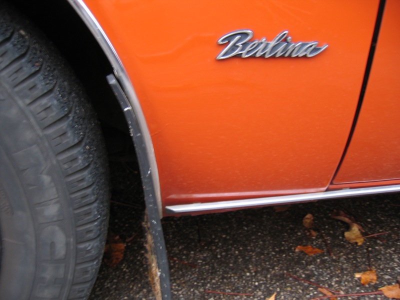 an orange car sits parked on the sidewalk