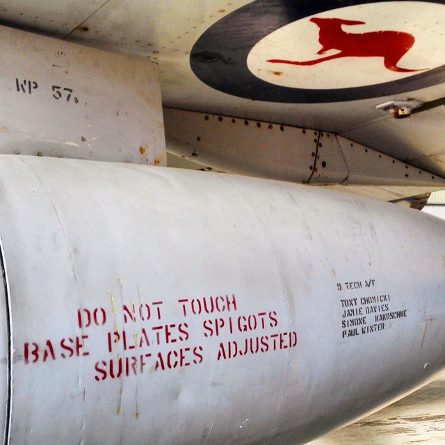 a large metal pipe under a plane with writing