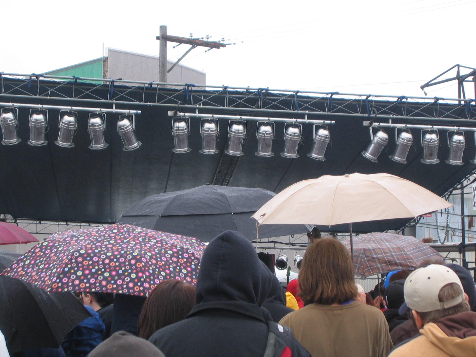 several people standing under umbrellas next to a stage