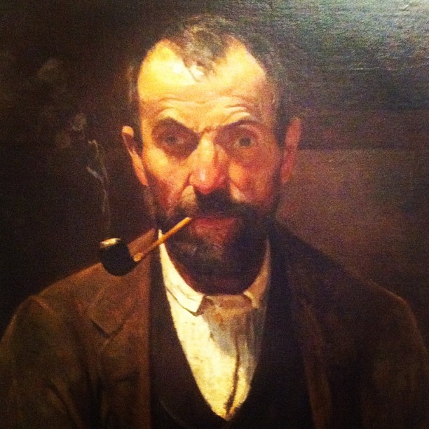 a man with a pipe in his mouth, next to a painting