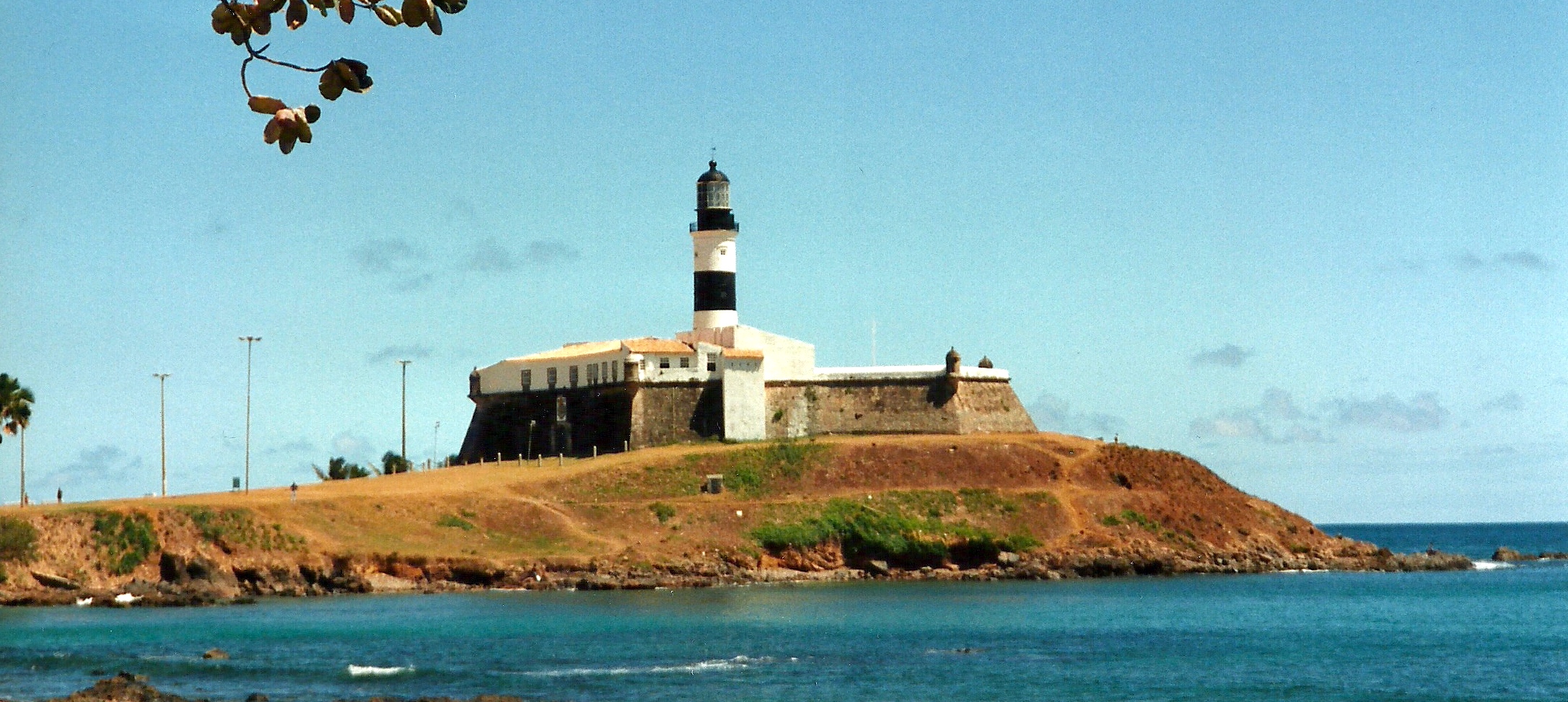 a white lighthouse on top of a hill near water