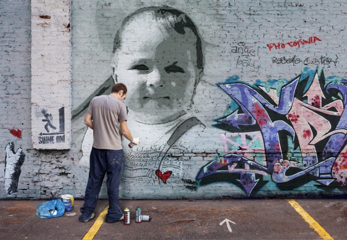 a person painting graffiti on a wall with a baby on it