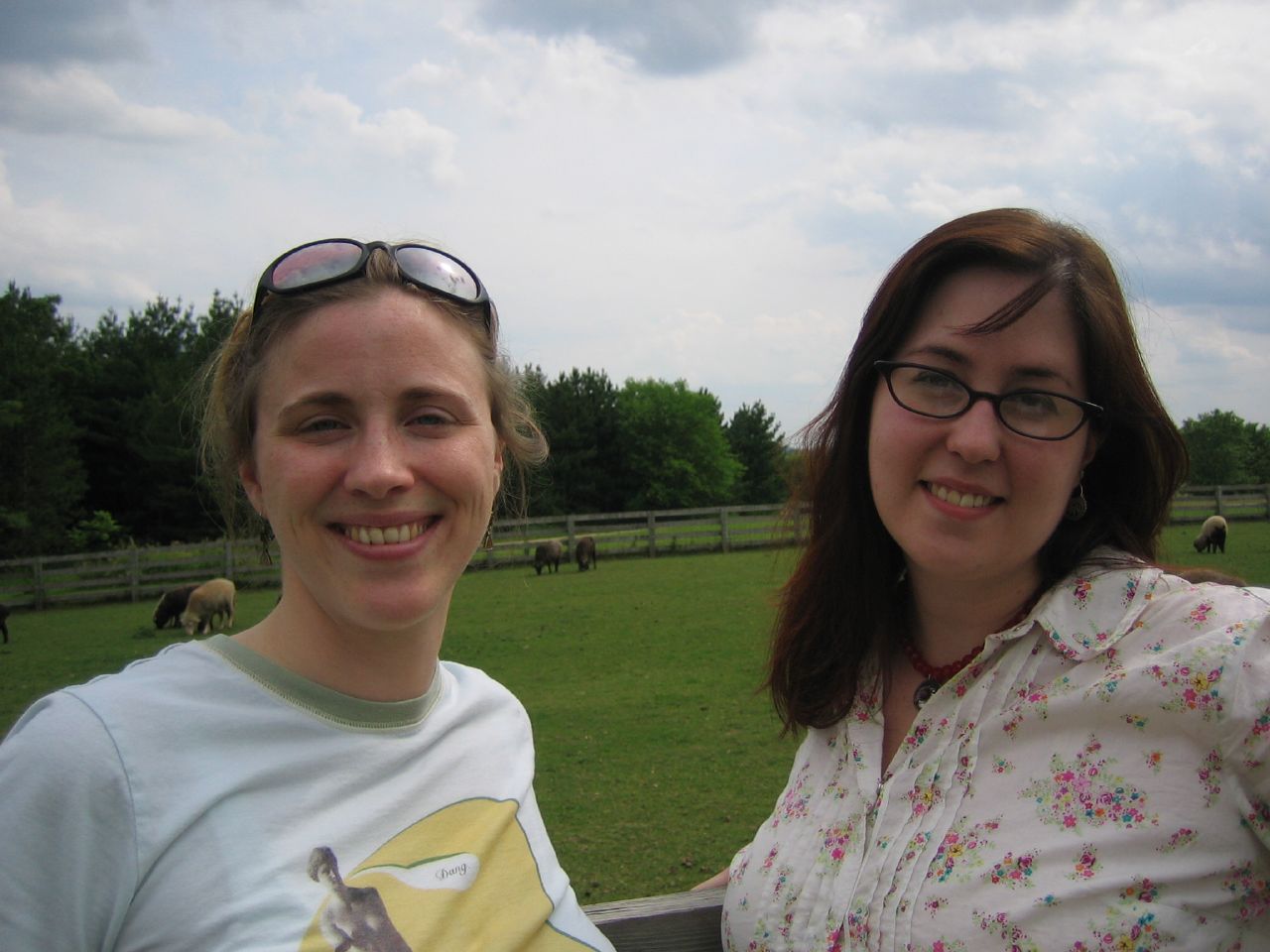 two women are posing with a green pasture behind them