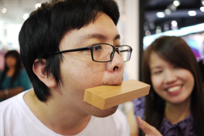 a man biting through a wooden block to eat a piece