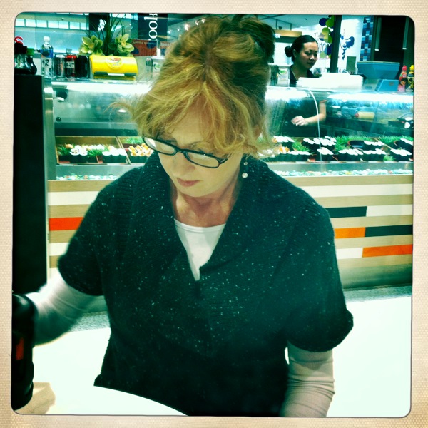 a woman wearing glasses at an empty deli counter