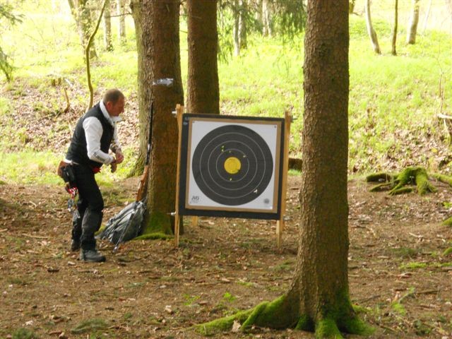 a man stands in front of a target with a rifle in the woods
