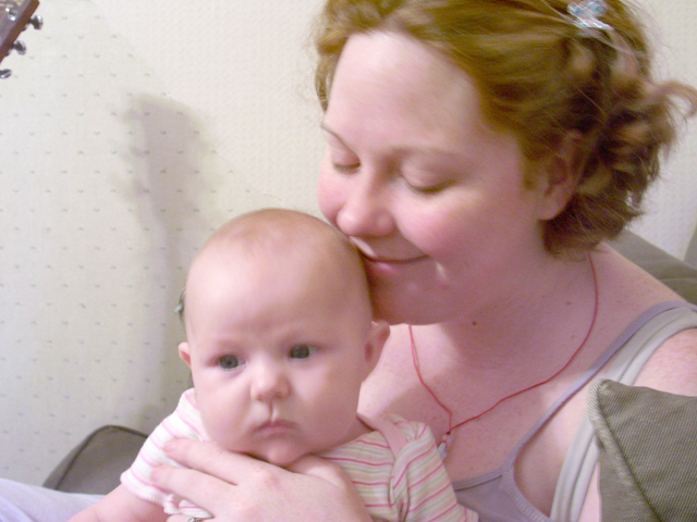 a woman holds a baby in her arms and looks to the side