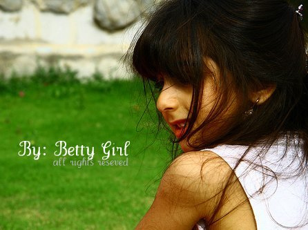 girl holding her hand out to the side with green grass in the background