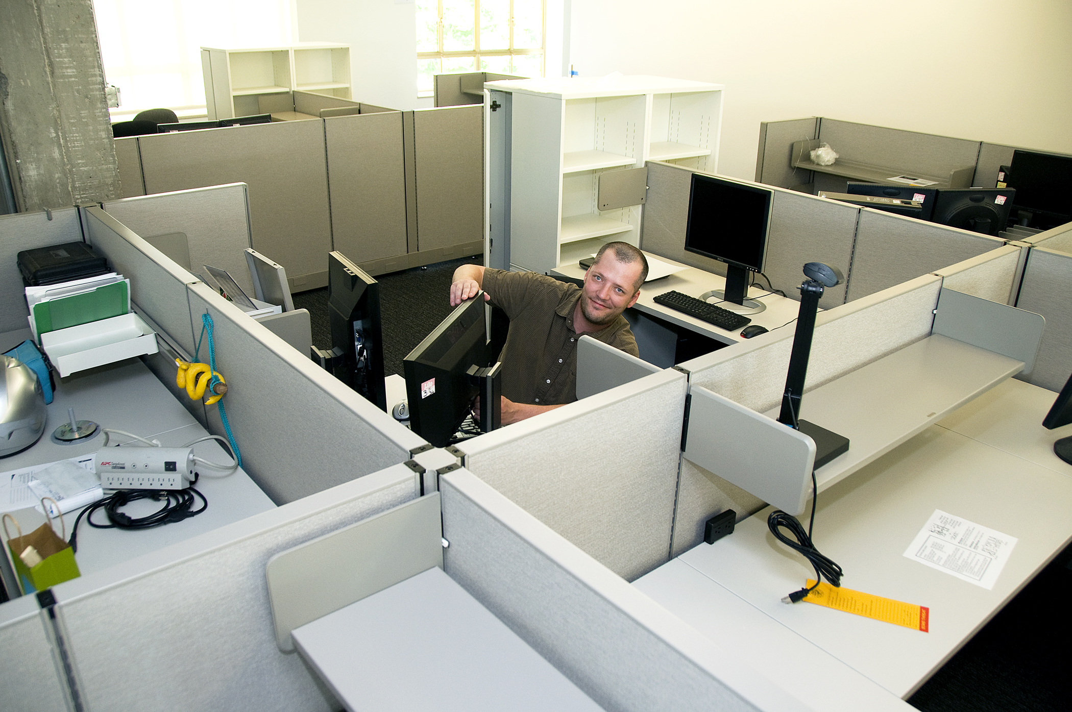 an office cubicle is shown with two cubicles and a man leaning over the top of the cubicle