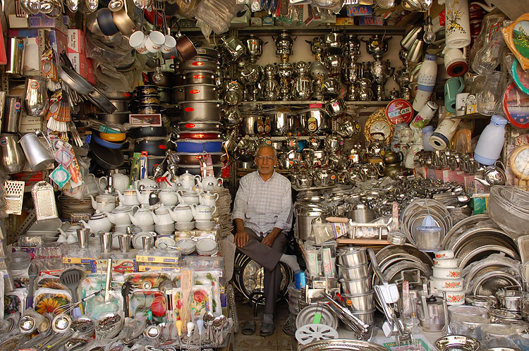 a man sits in a store filled with lots of dishes