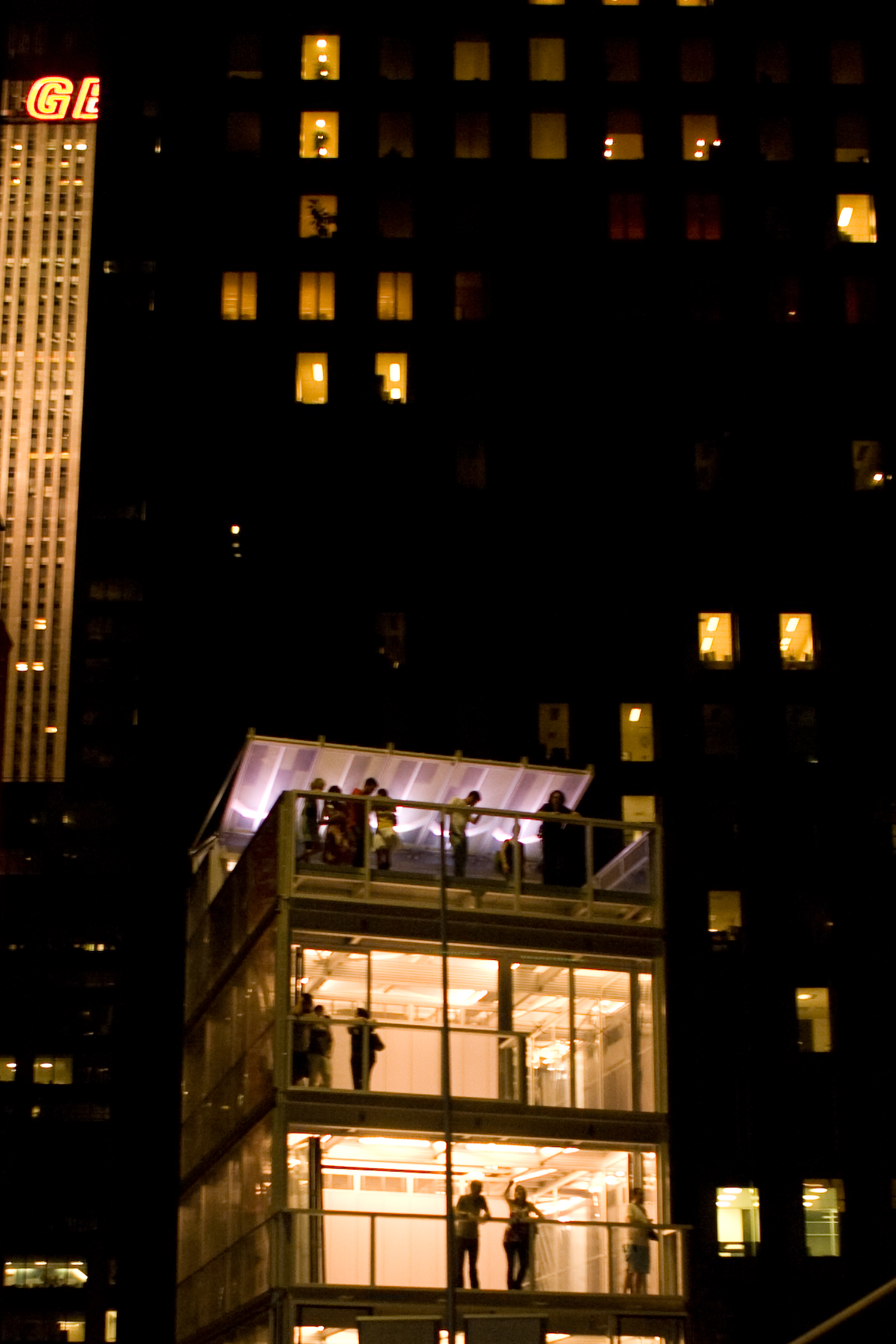 a night scene with a building that has lit up windows and people standing inside