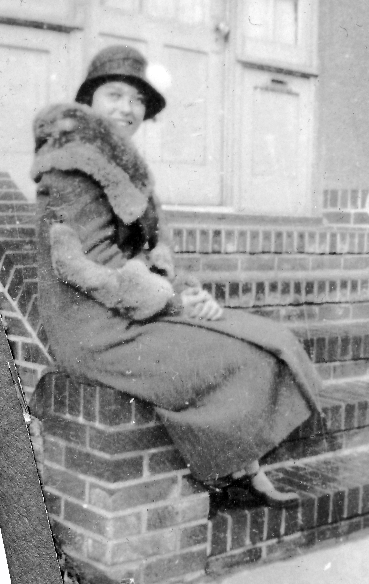 a woman is sitting on a brick wall and posing for a picture