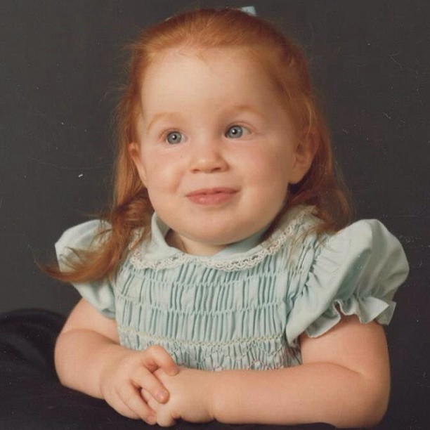 a little girl with red hair wearing a green dress