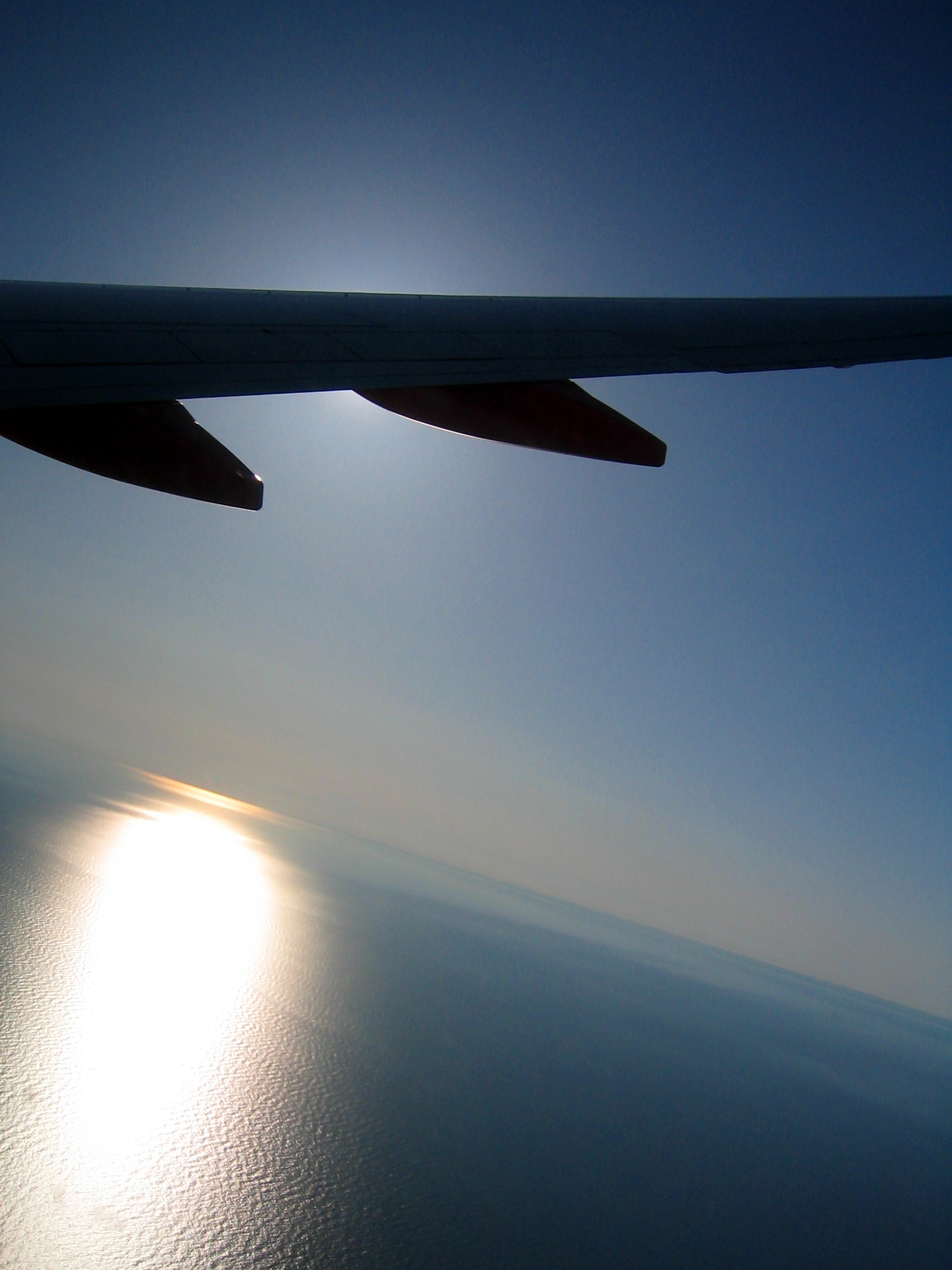 the back end of an airplane wing is shown with the sun shining through the plane wings