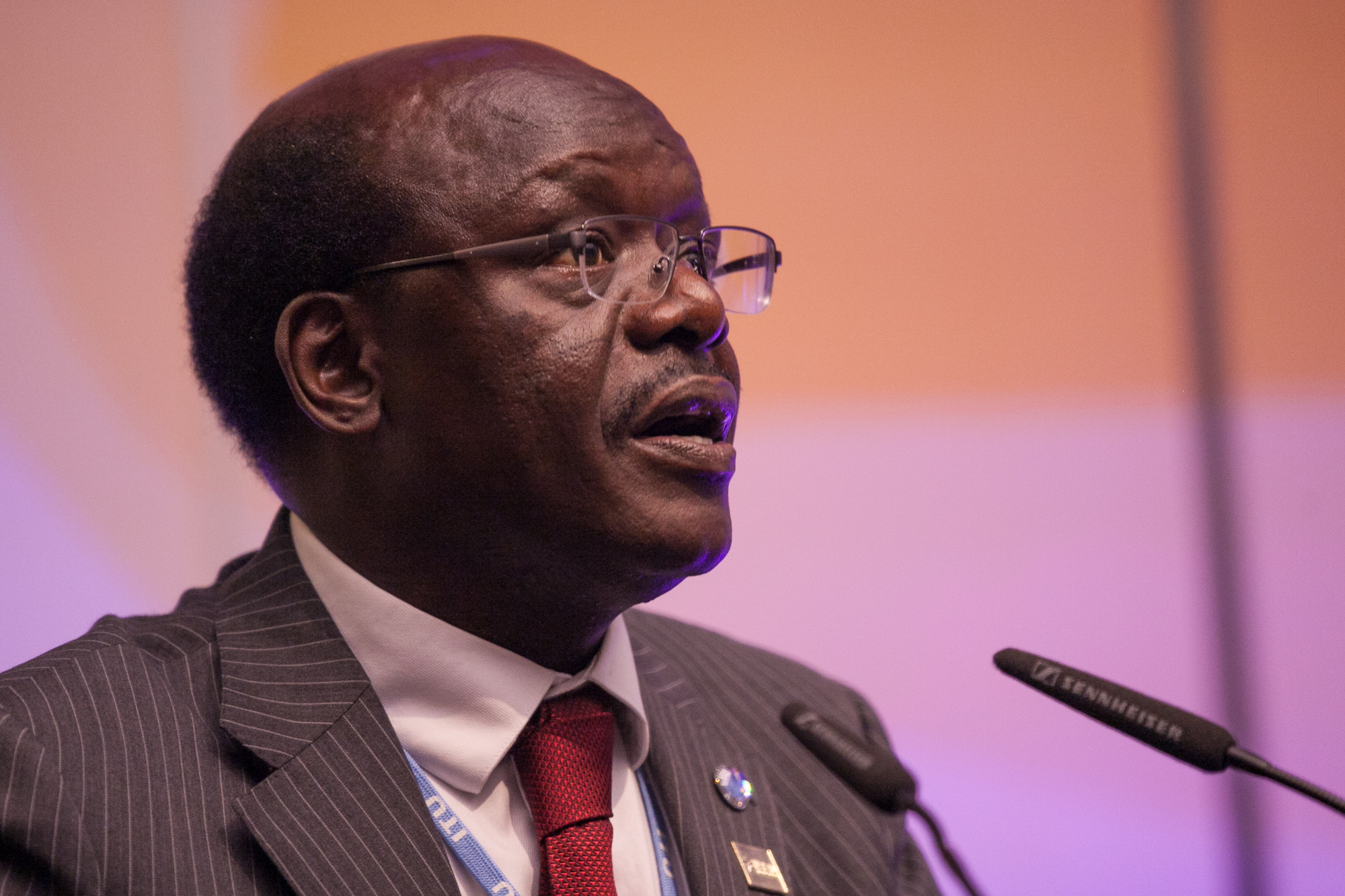 a man wearing glasses speaking into microphones