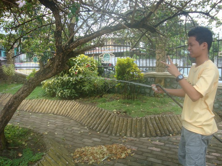 a boy watering a tree with a garden hose
