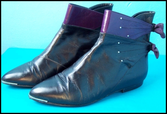 a pair of leather shoes with metal details and a pink heel