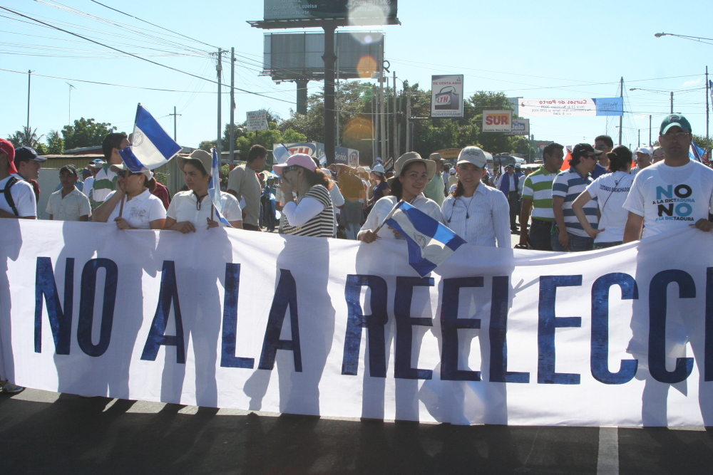 people holding up a banner that says no la relecci