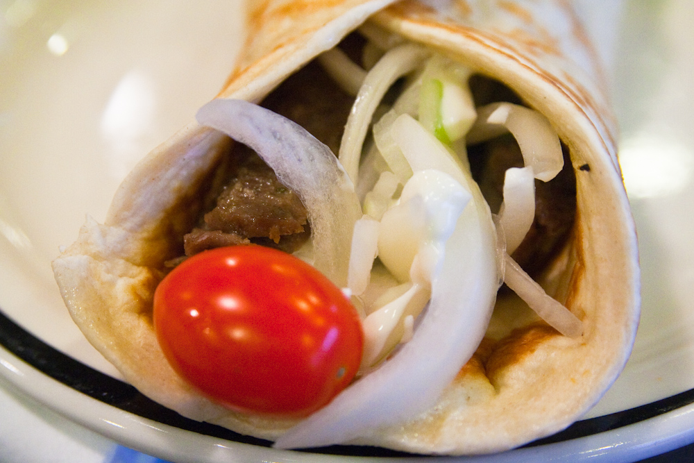 a taco filled with meat and veggies on a white plate