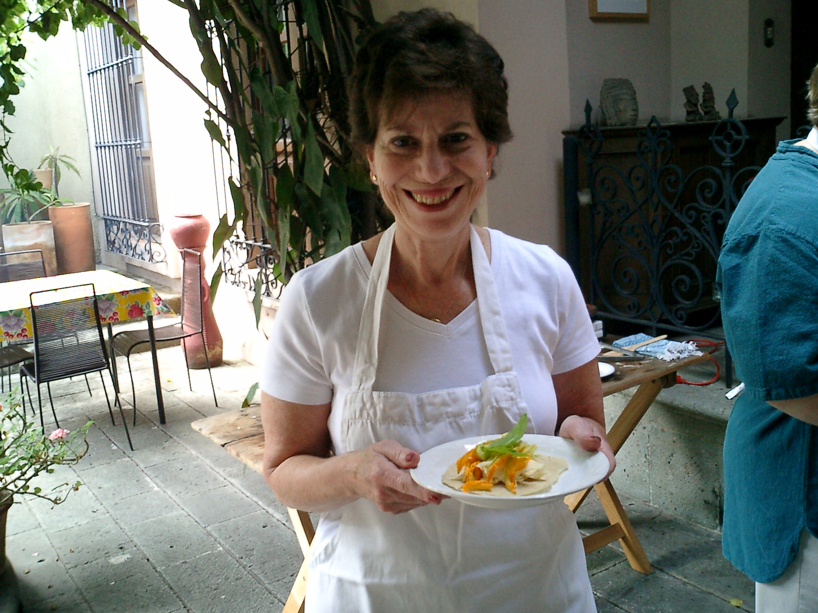 the lady in an apron is holding her plate full of food