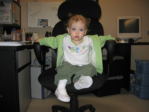 young child with one foot on black chair in office
