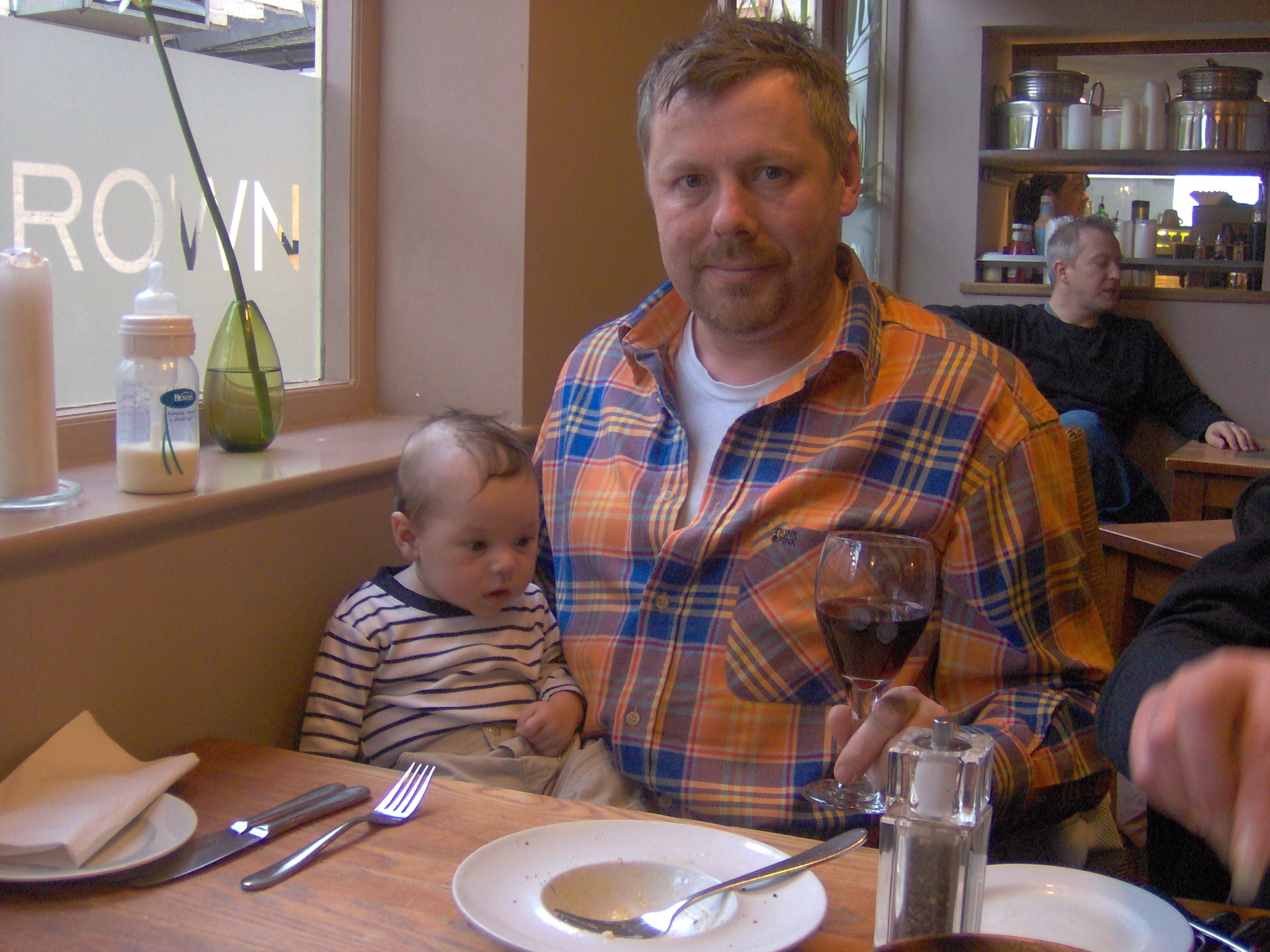 a man holding a baby while sitting at a table