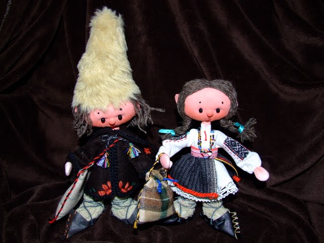 two dolls of people wearing dresses with a black background