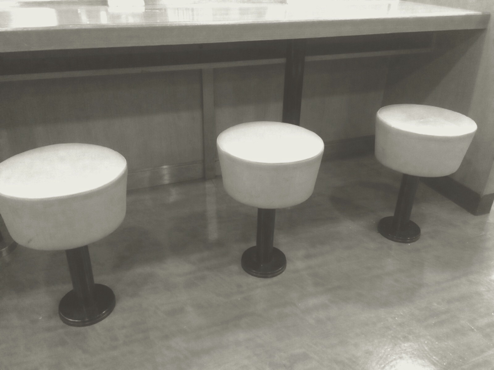 three white stools are sitting in the corner of a bar