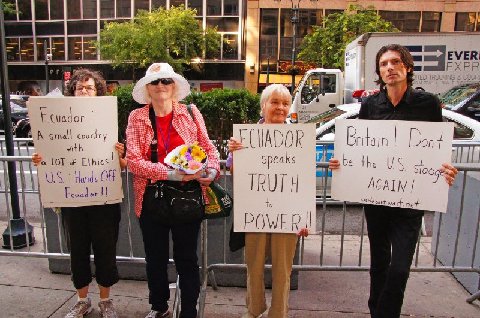 four people holding up signs behind a metal fence