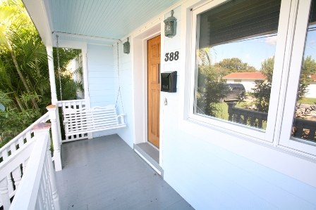 a house front porch with white painted siding and a wood door