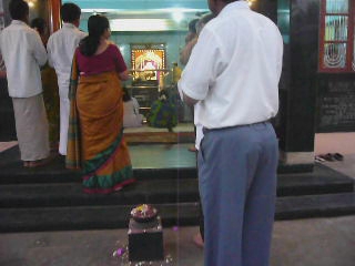 man in blue pants standing in front of a small cake