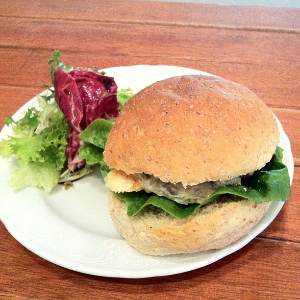 a sandwich on a white plate with lettuce and tomato salad