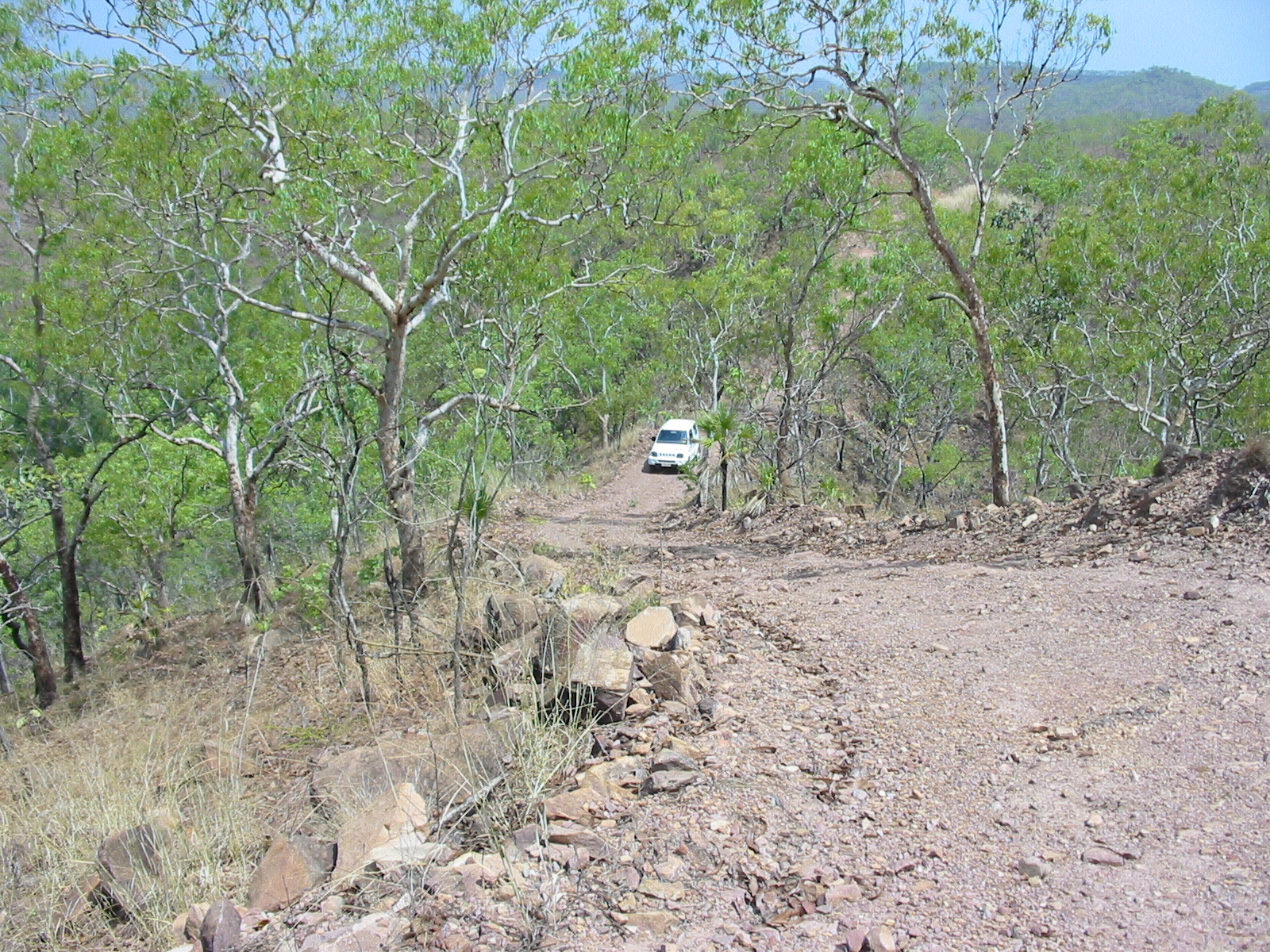 the car is driving down the dirt road