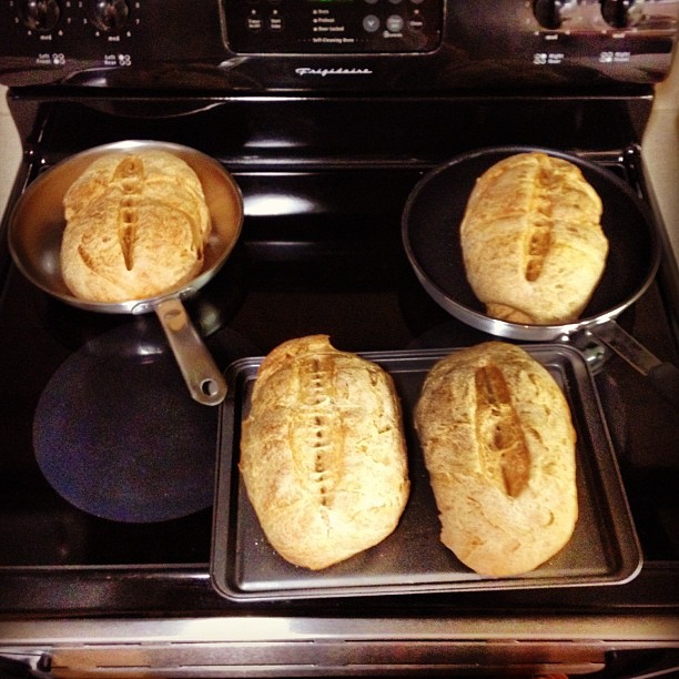 four pans on the stove filled with bread