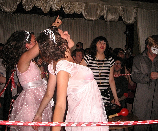 several girls in white dresses and head coverings dance at an event