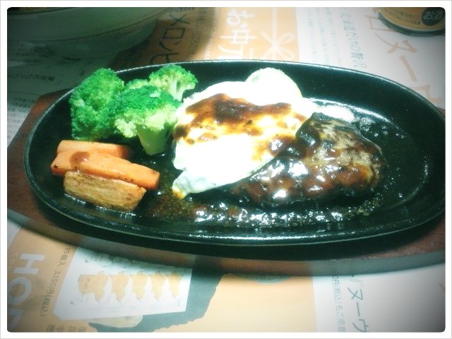 a black plate filled with meat, vegetables and grits