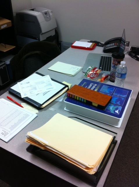 a desk with some paper and several other items on it