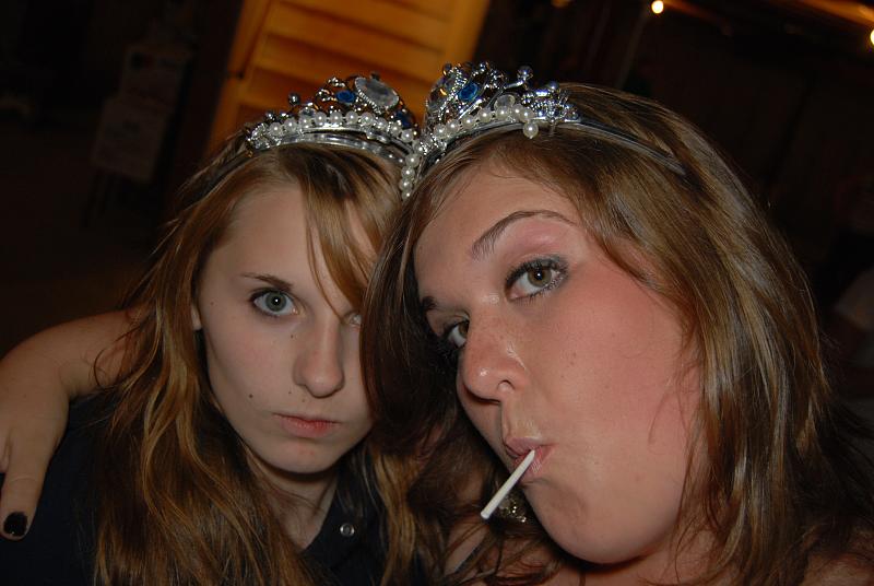 two beautiful young ladies wearing crowns smoking cigarettes