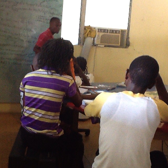 children in a classroom sitting around a blackboard